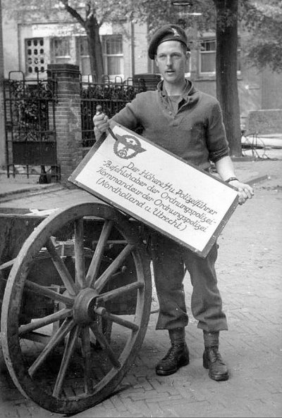 Soldaat toont na de bevrijding een gesloopt wandbord van de Duitse bezetter, Amsterdam (1945).JPG