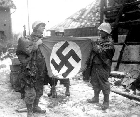 A couple of G.I.'s holding a captured German flag during the Battle of the Bulge..jpg