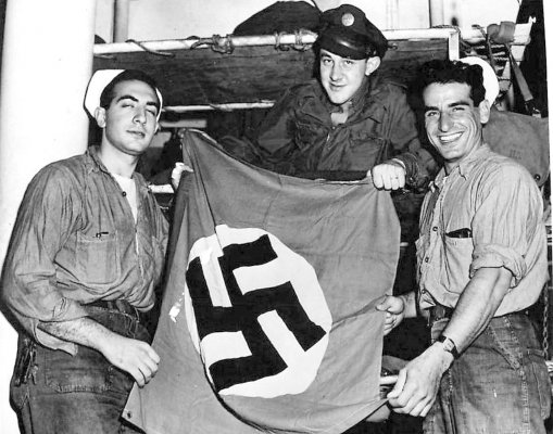 Pvt. William Walker displays his captured German flag for the camera with the help of a few Coas.jpg