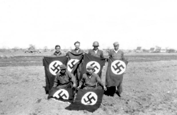 Six U.S. soldiers holding Nazi flags in a field. .jpg